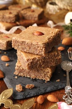 three pieces of food sitting on top of a black slate board next to some nuts