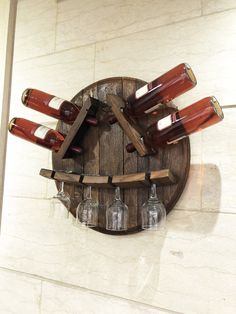 a clock made out of wine bottles on a wooden shelf with four glasses in it