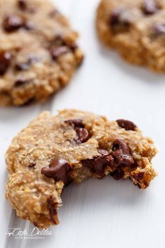 an oatmeal cookie with chocolate chips is broken in half on a white surface