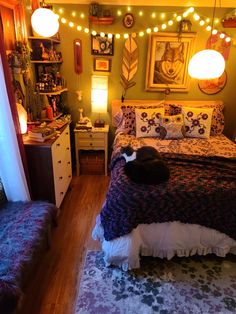 a cat laying on top of a bed in a room with lights strung above it