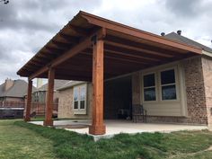 a covered patio in front of a brick house