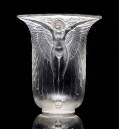 a glass vase with an angel design on the front and side, sitting on a black background