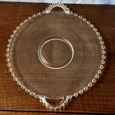 a glass plate with two silver rings on it sitting on top of a wooden table