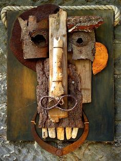 a sculpture made out of wood and rope on top of a wooden plaque with two faces