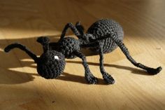 a crocheted black spider sitting on top of a wooden table next to a light