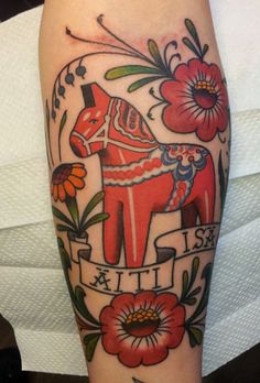 a tattoo with an image of a horse and flowers on the arm, done by person