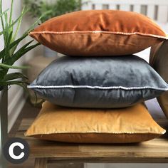 four pillows stacked on top of each other in front of a potted plant and window sill