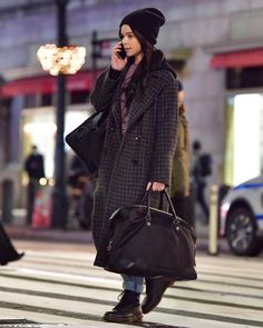 a woman is walking down the street talking on her cell phone and holding two bags