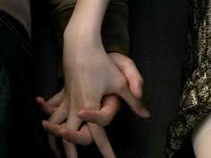 two people holding their hands together on a bus or subway seat, with one person's hand in the other