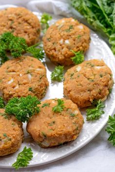 several crab cakes on a white plate with parsley