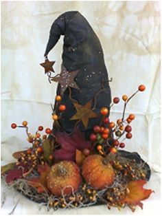 a witches hat sitting on top of pumpkins and berries