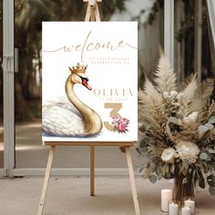 a welcome sign with a swan on it next to flowers and candles in front of a glass door