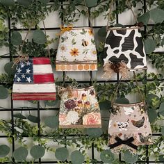 four purses are hanging on a metal rack with ivy growing around them and one is decorated with an american flag