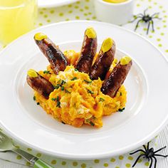 eggs and sausages are served on a white plate with spider web decorations around it