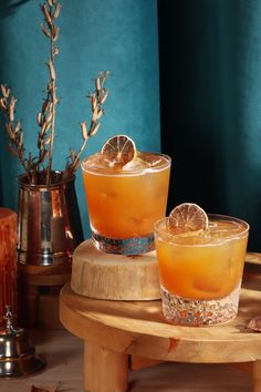 two glasses filled with orange juice sitting on top of a wooden table