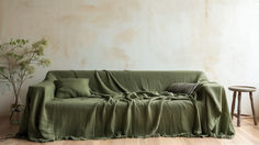 a living room with a couch covered in a green blanket next to a small table