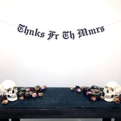 two skulls are sitting on a table with flowers in front of the banner that says thinks it's mums