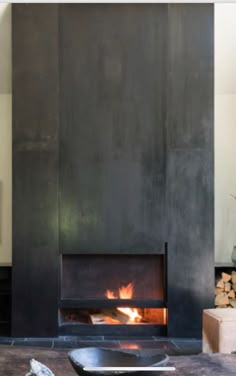 a living room with a fire place in the center and wood stacked on the floor