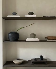 three shelves with vases and books on them