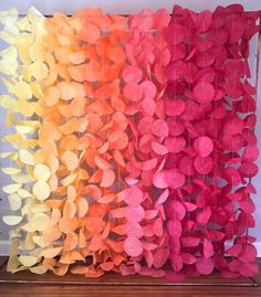 some paper flowers are hanging on the wall in front of a window with curtains made out of them