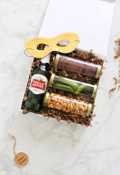 an open gift box filled with wine, nuts and other items on a marble surface