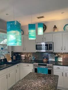 a kitchen with marble counter tops and blue lights hanging from the ceiling over the stove