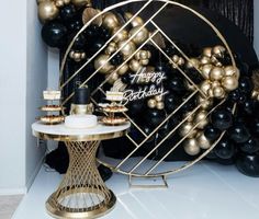 a black and gold birthday party with balloons, cake and desserts on the table