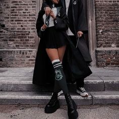 two people dressed in harry potter costumes standing on the street with one holding an umbrella