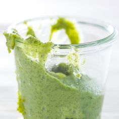 a green smoothie in a glass cup with some sort of garnish on top