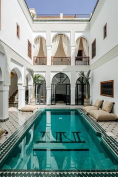 an indoor swimming pool in the middle of a large building with white walls and arches