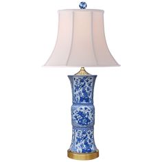 a blue and white table lamp with a light shade on the top, sitting against a white background