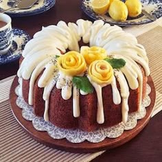 a bundt cake with lemons and icing on a plate next to tea cups