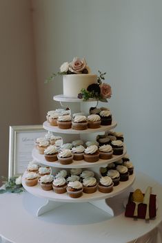 a three tiered cake with cupcakes on it