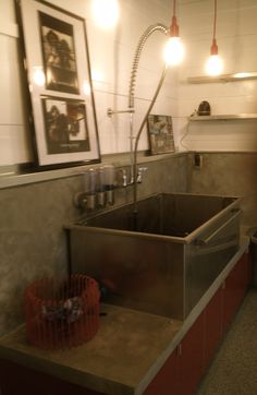 a kitchen with a sink, counter and hanging lights above the sink are pictures on the wall