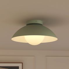 a green ceiling light hanging from the ceiling in a room with two pictures on the wall