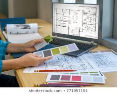 a person sitting at a desk working on a laptop computer with architectural drawings and color swatches