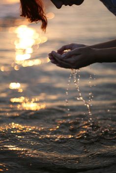 a woman is standing in the water with her hands out