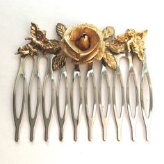 This listing is for a silver toned hair comb adorned with a vintage gold toned rose jewelry piece. 2 gold toned cherubs on each side. The comb is 2 inches wide. Costume jewelry.  Please visit my shop for more hair combs with vintage jewelry and unique jewelry! I combine shipping. First Class packages will be shipped bubble wrapped inside of a padded envelope. Priority Mail packages will be shipped bubble wrapped in a box. Any displays not included in sale unless otherwise noted. Coin in photo for size reference. Feel free to reach out with any questions, thank you for visiting my shop! Toned Hair, Vintage Comb, Decorative Hair Combs, Bridal Accessory, Vintage Hair Combs, Vintage Rhinestone Brooch, Vintage Cameo, Rose Jewelry, Tone Hair