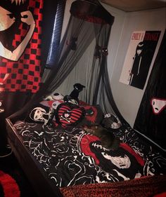 a cat laying on top of a bed covered in black and red sheets with skulls