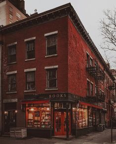 an old red brick building on the corner of a street with bookshelves in front of it