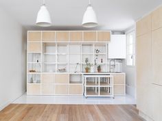 an empty kitchen with white cabinets and wood flooring is shown in this image, there are two pendant lights above the island