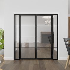 an empty room with wooden floors and glass doors leading to a dining area that has a black table and chairs