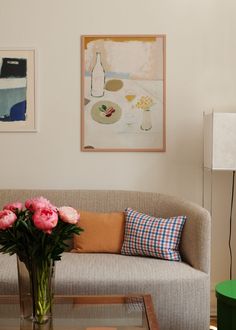 a living room filled with furniture and flowers on top of a coffee table in front of a painting