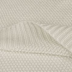 a white knitted blanket folded up on top of each other