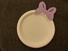 a white paper plate with a pink bow on the front and bottom, sitting on a black surface