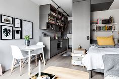 a bedroom with a bed, table and chairs in it next to a small kitchen