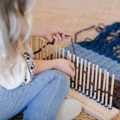 a woman is sitting on the floor working on an item with yarn and crochet