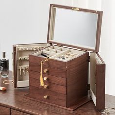 an open wooden jewelry box sitting on top of a table next to a mirror and other items