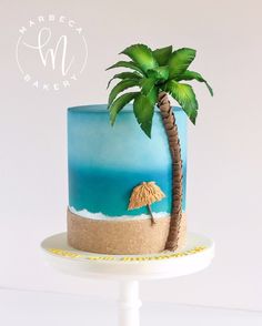 there is a blue cake with a palm tree on the top and sand underneath it