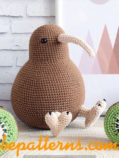 a crocheted kiwi sitting on top of a table next to two pieces of fruit